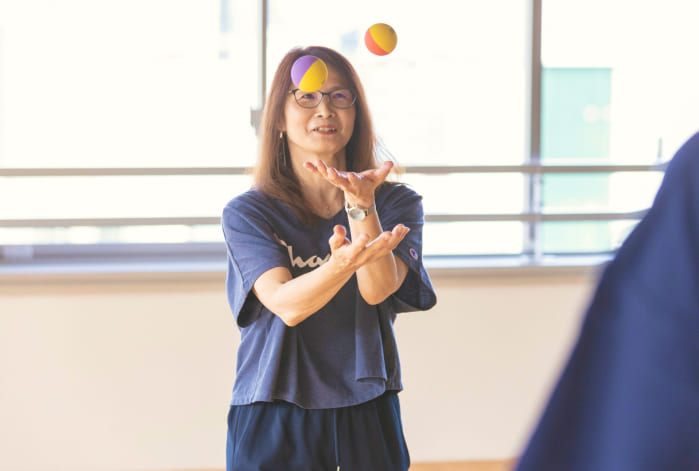 写真：女性が宙を舞っている２つのボールを受け取ろうとしている様子